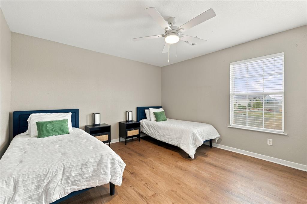 Neutral wall tones, wood-finish flooring, ceiling fan with integrated light fixture, and horizontal blind window treatment