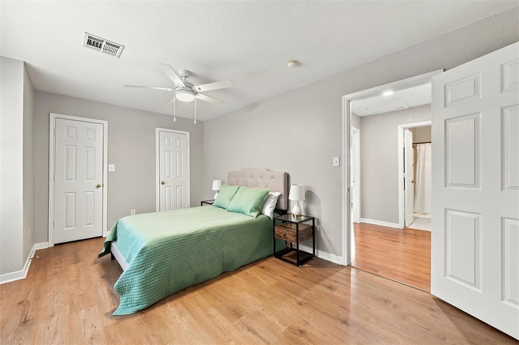 Room featuring wood-finish flooring, a white ceiling fan with integrated lighting, and multiple interior doors with white finish