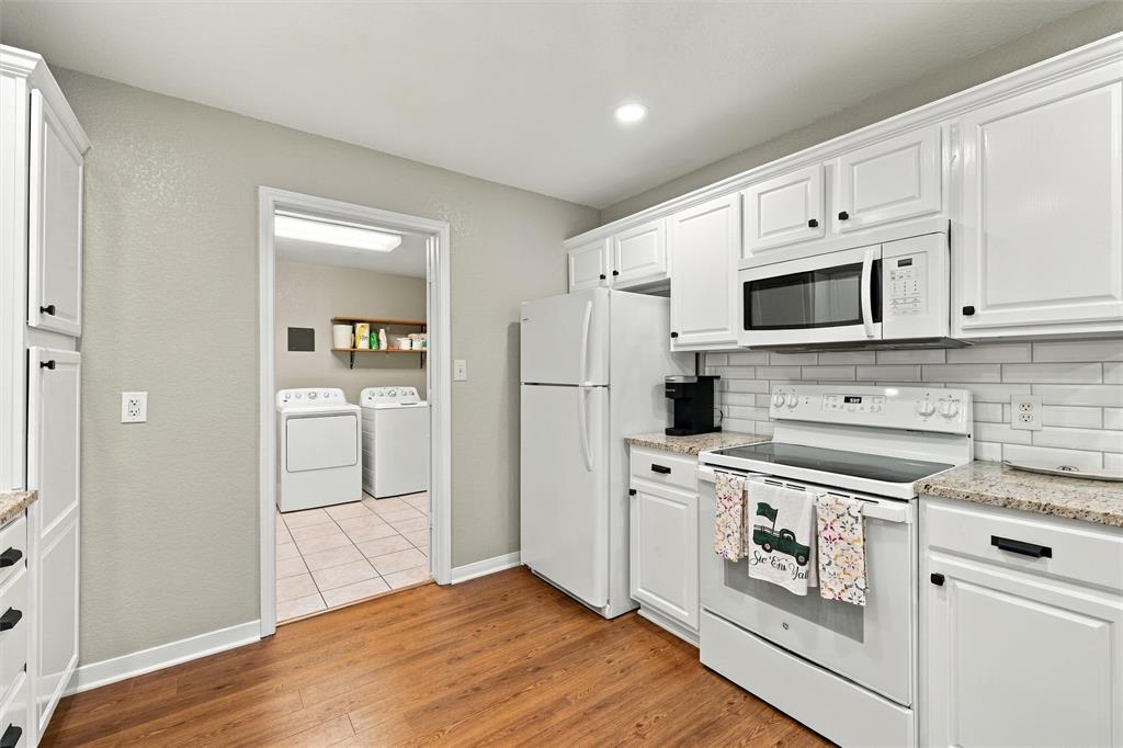 Kitchen featuring white cabinetry, subway tile backsplash, stone-finish countertops, and wood-finish flooring