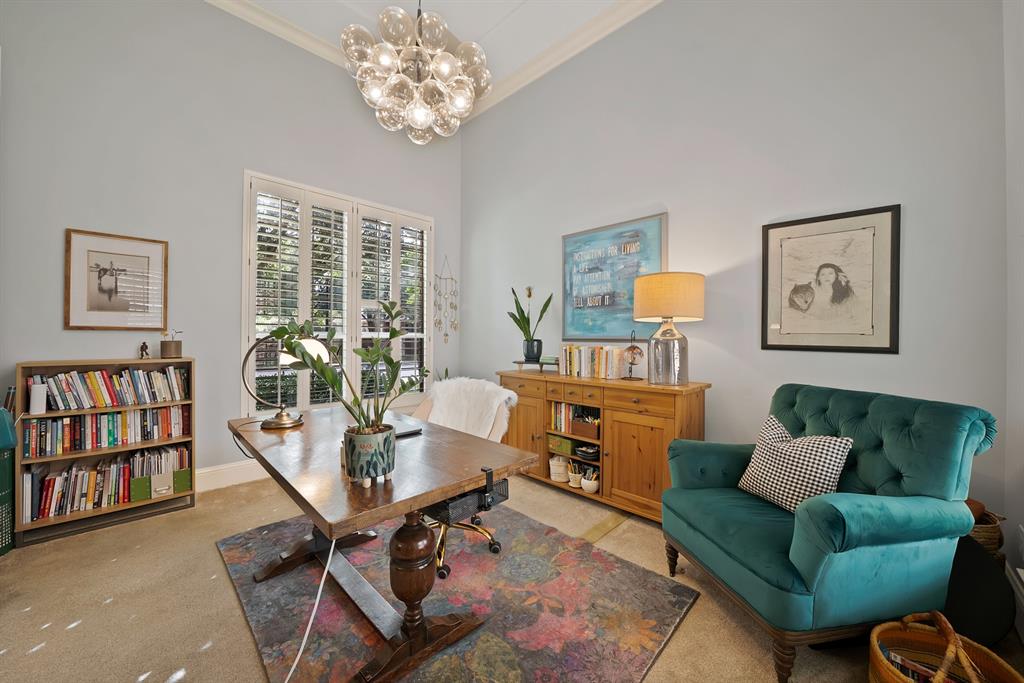 High-ceiling room featuring a statement multi-globe chandelier and white plantation shutters