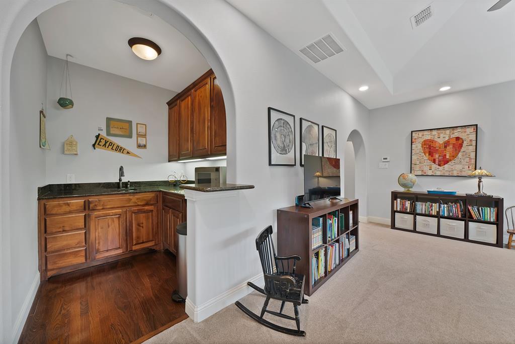 Arched entryway featuring stained wood cabinetry, stone countertops, dark-finish faucet, and recessed lighting
