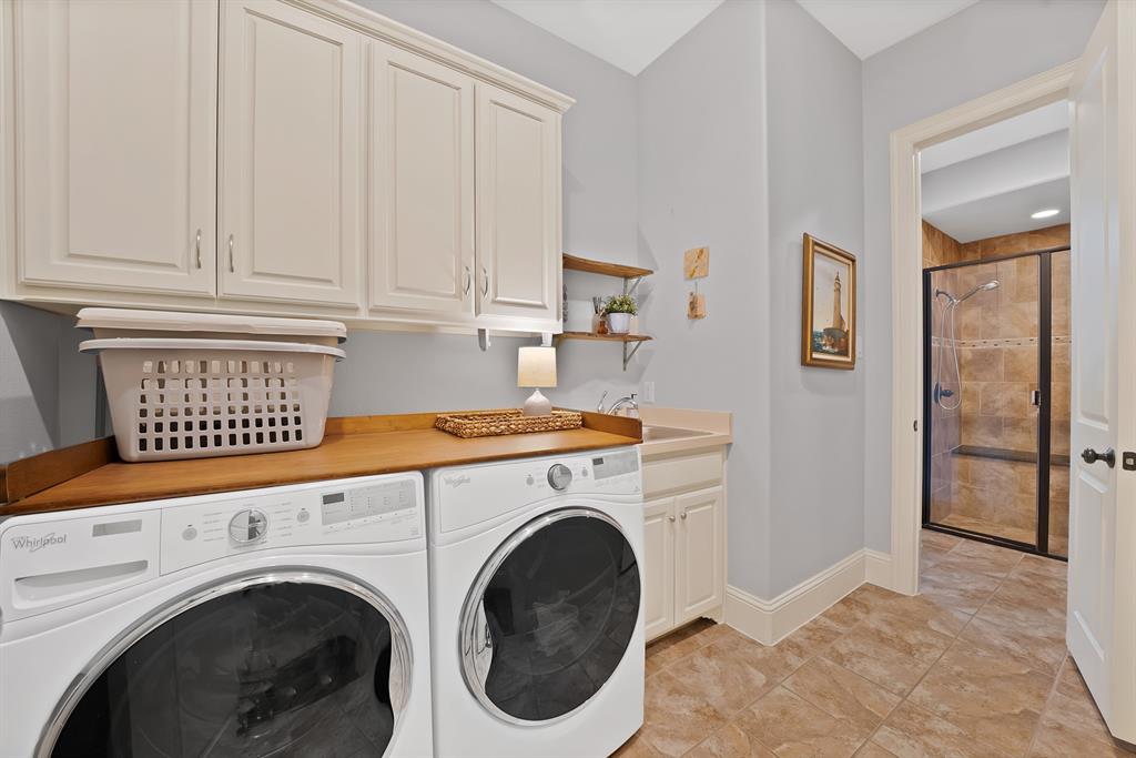 Laundry room featuring white cabinetry, wood-surface countertop, built-in utility sink, and tile flooring