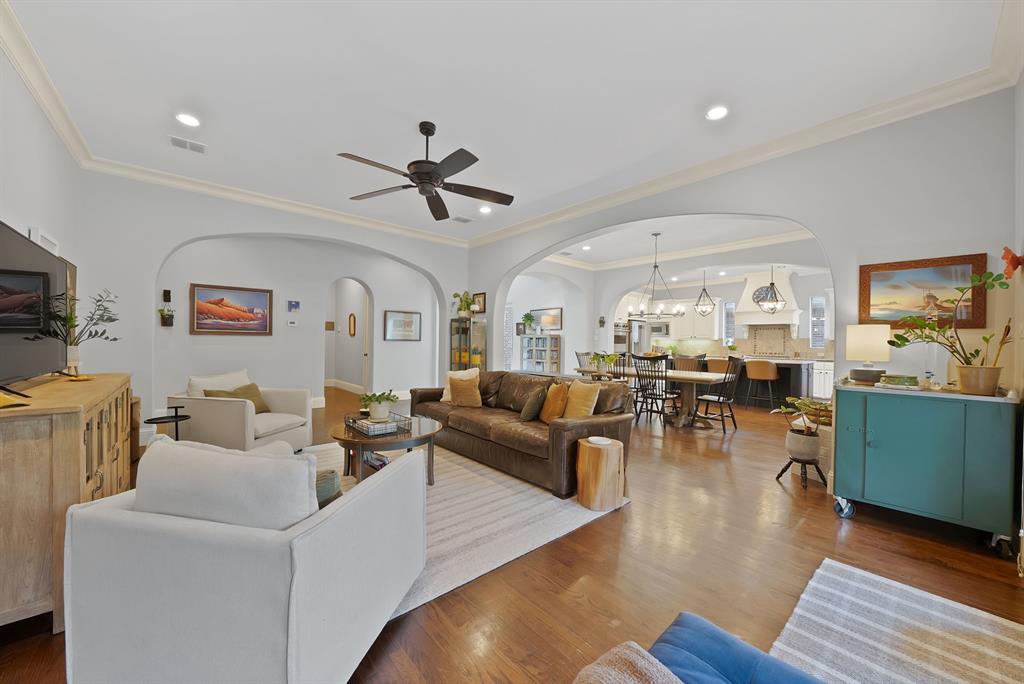 Open-concept living space featuring wood-finish flooring, recessed lighting, crown molding, arched entryways, and a ceiling fan