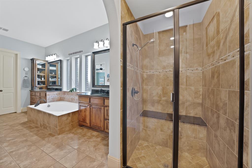 Bathroom featuring a tiled shower enclosure with a built-in bench, jetted soaking tub, dark wood cabinetry, and multiple light fixtures