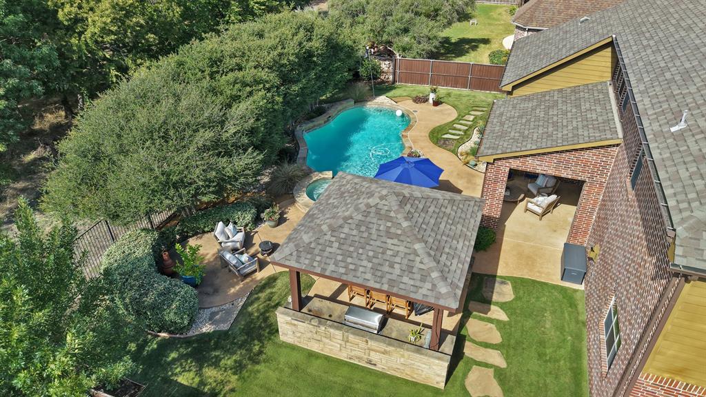 Backyard featuring an in-ground swimming pool, integrated spa, covered patio, stone-veneer outdoor kitchen, and a detached gazebo with shingled roofing