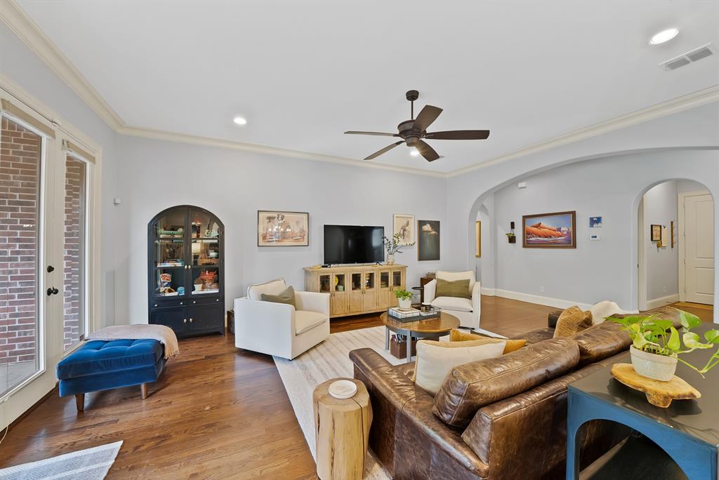 Living area featuring hardwood flooring, recessed lighting, crown molding, arched entryways, and a ceiling fan