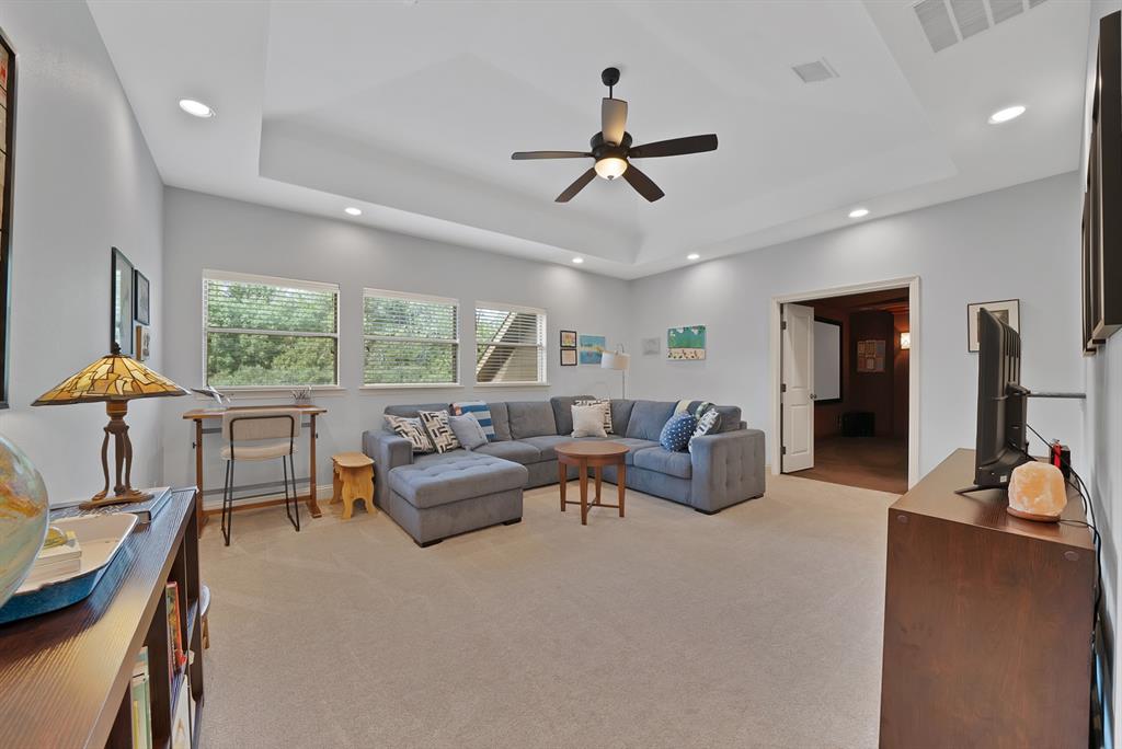 Tray ceiling with recessed lighting, central ceiling fan, multi-pane windows, and neutral carpeting