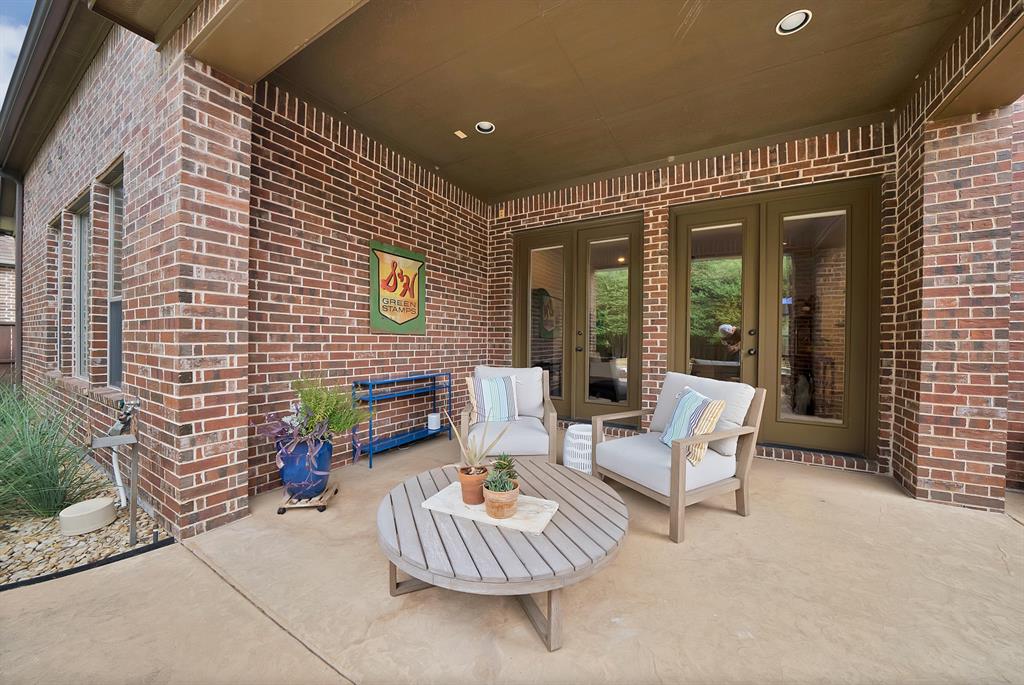 Covered patio featuring red brick masonry, a solid-surface floor, recessed lighting, and dual glass-paneled exterior doors