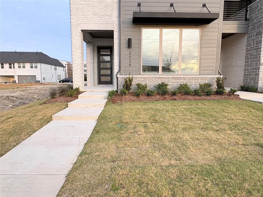 Modern exterior featuring a combination of brick and horizontal siding, a multi-pane glass entry door, stone-veneer accents, and a contemporary metal window awning Modern exterior featuring a combination of brick and horizontal siding, a multi-pane glass entry door, stone-veneer accents, and a contemporary metal window awning