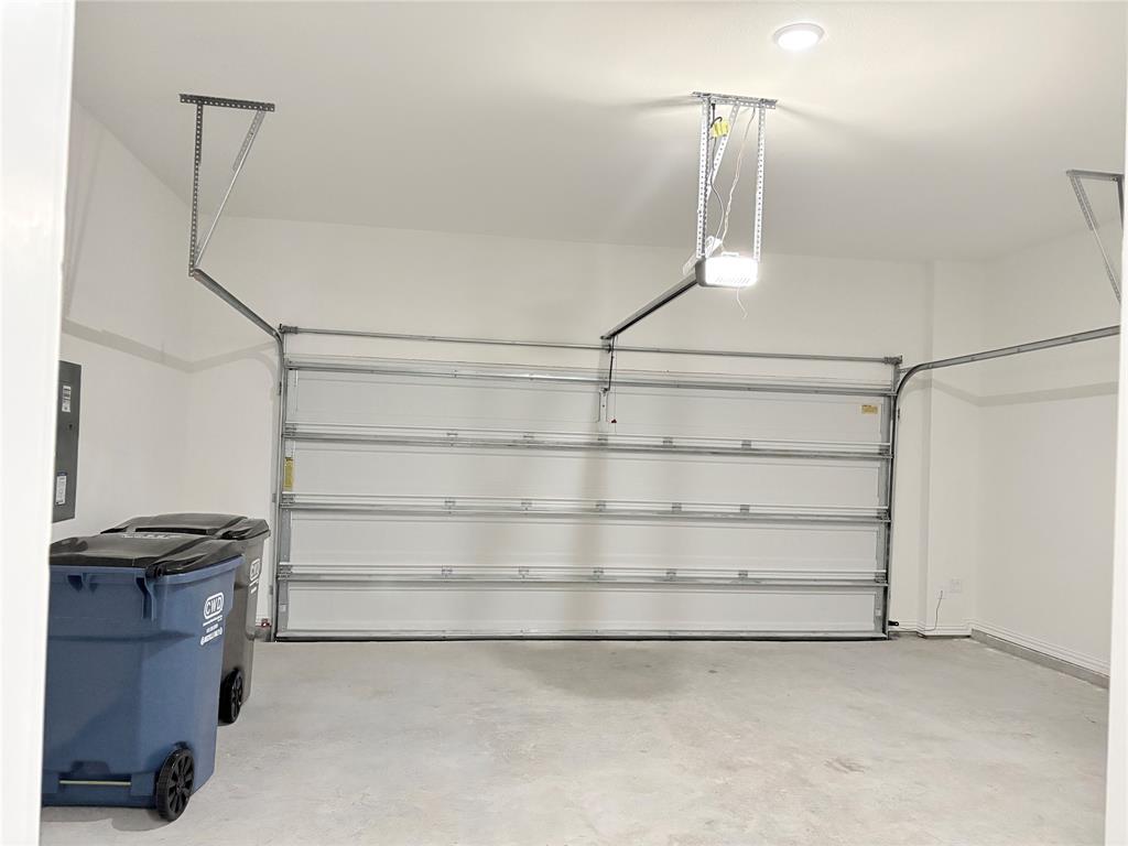 Enclosed garage with a white sectional door, automatic opener, recessed lighting, and a concrete floor