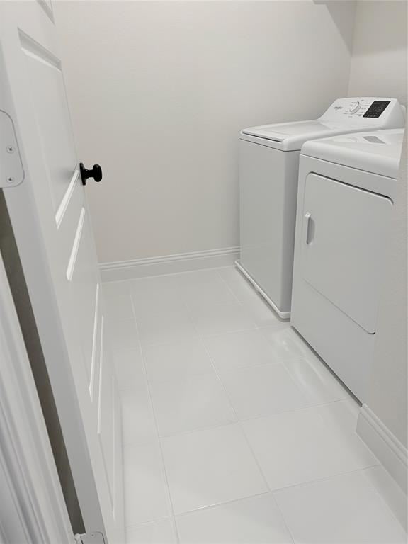 Utility room featuring white ceramic tile flooring and a solid-core door with matte black hardware