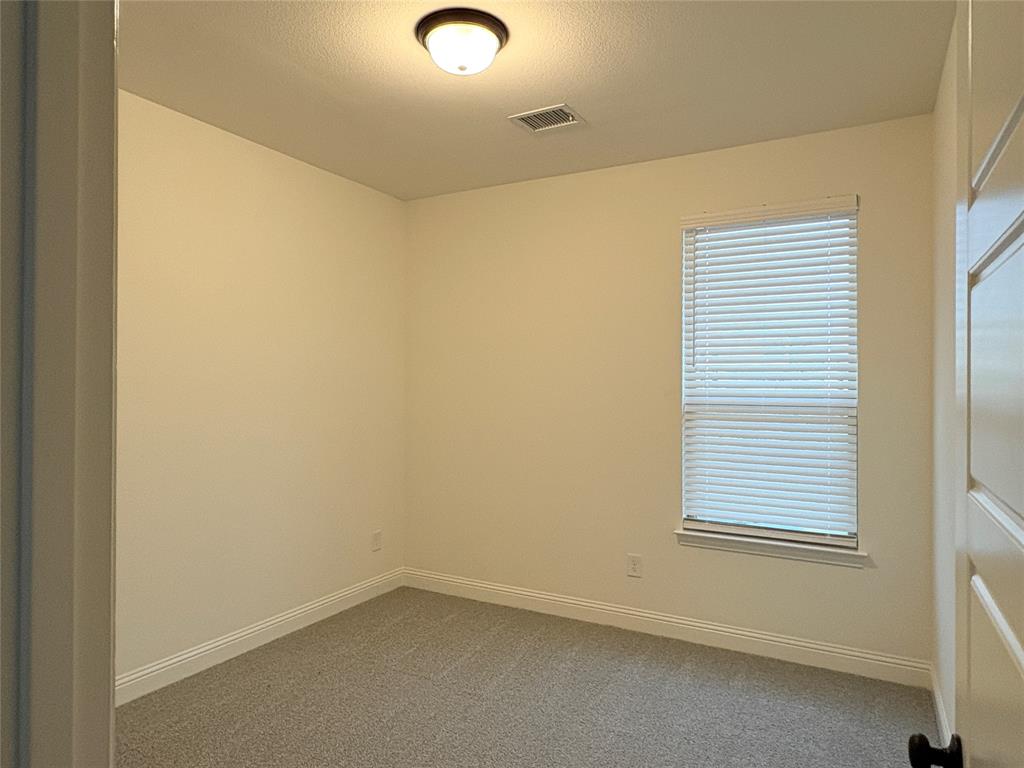 Neutral-toned interior space featuring wall-to-wall carpeting, a single window with horizontal blinds, and a dome-style flush-mount ceiling light