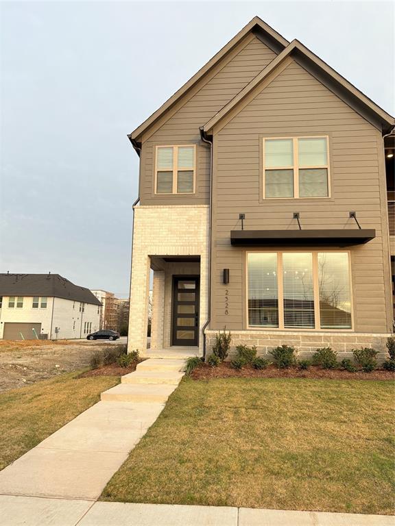 Multi-story exterior featuring horizontal siding, light-toned masonry accents, a modern multi-panel entry door, and a metal-frame window awning Multi-story exterior featuring horizontal siding, light-toned masonry accents, a modern multi-panel entry door, and a metal-frame window awning