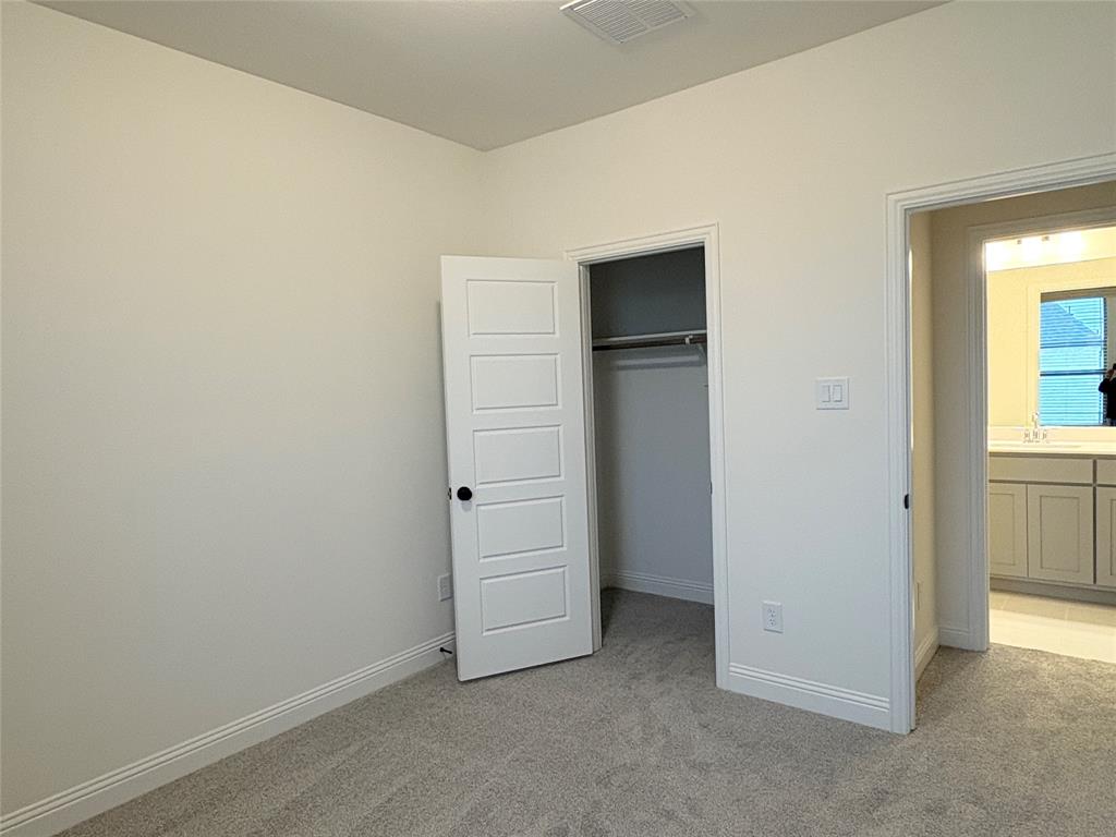Neutral-toned carpeting, five-panel interior door, built-in closet, and light-toned cabinetry with light-colored countertops