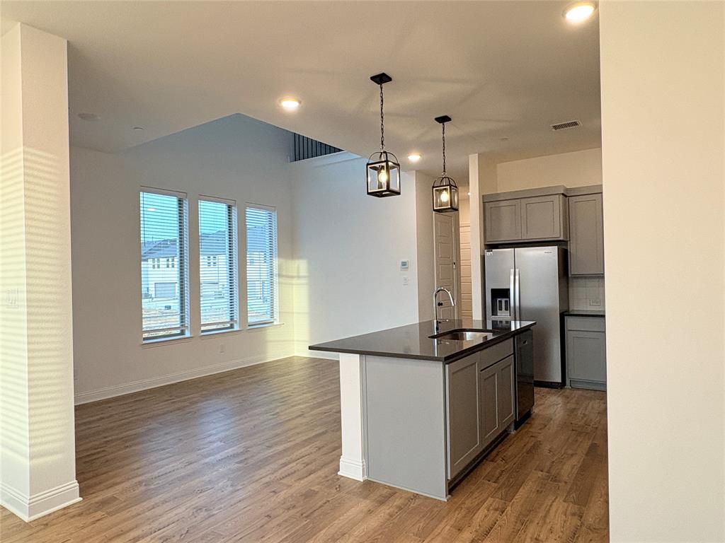 Kitchen featuring wood-finish flooring, a central island with a stone-surface countertop, recessed lighting, and dual pendant light fixtures