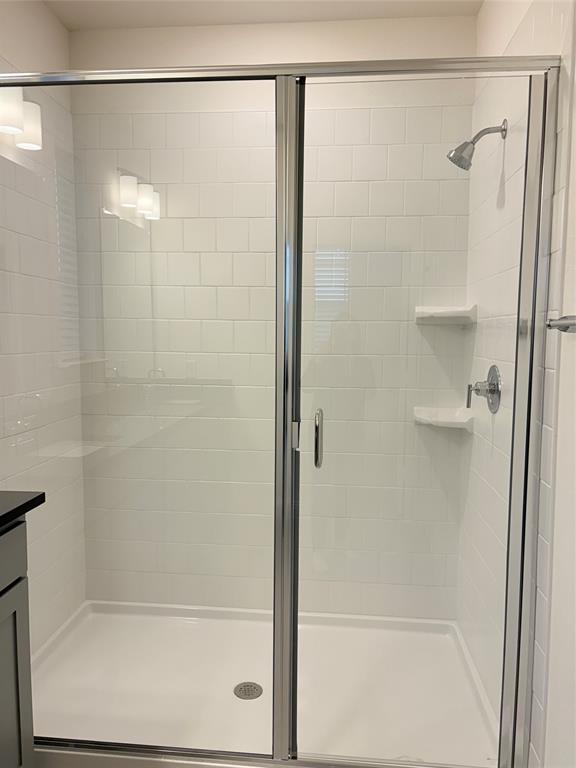 Walk-in shower featuring white subway-style wall tile, built-in shelving, chrome fixtures, and a glass enclosure with a metal frame