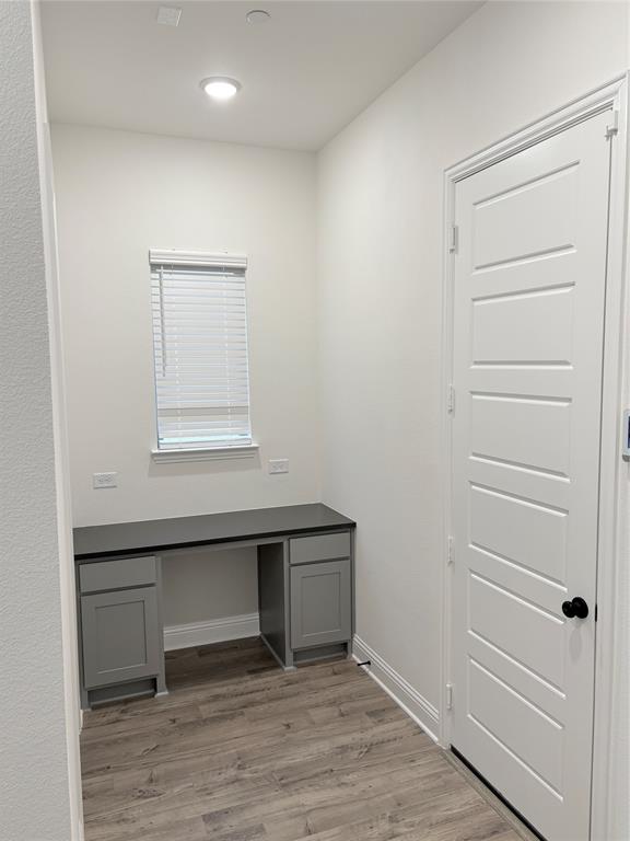 Built-in desk featuring shaker-style cabinetry, dark solid-surface countertop, recessed ceiling lighting, and wood-finish flooring