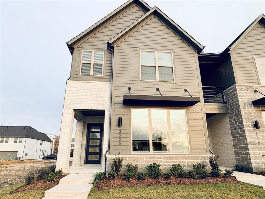 Exterior featuring horizontal lap siding, white brick masonry, a modern multi-panel glass front door, metal awning, and wall-mounted exterior lighting Exterior featuring horizontal lap siding, white brick masonry, a modern multi-panel glass front door, metal awning, and wall-mounted exterior lighting