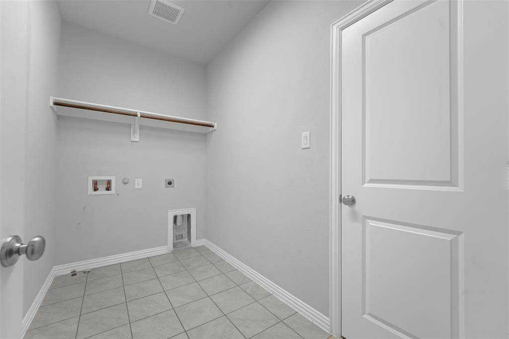 Utility room featuring a built-in shelf with a hanging rod, tile flooring, and light gray wall paint