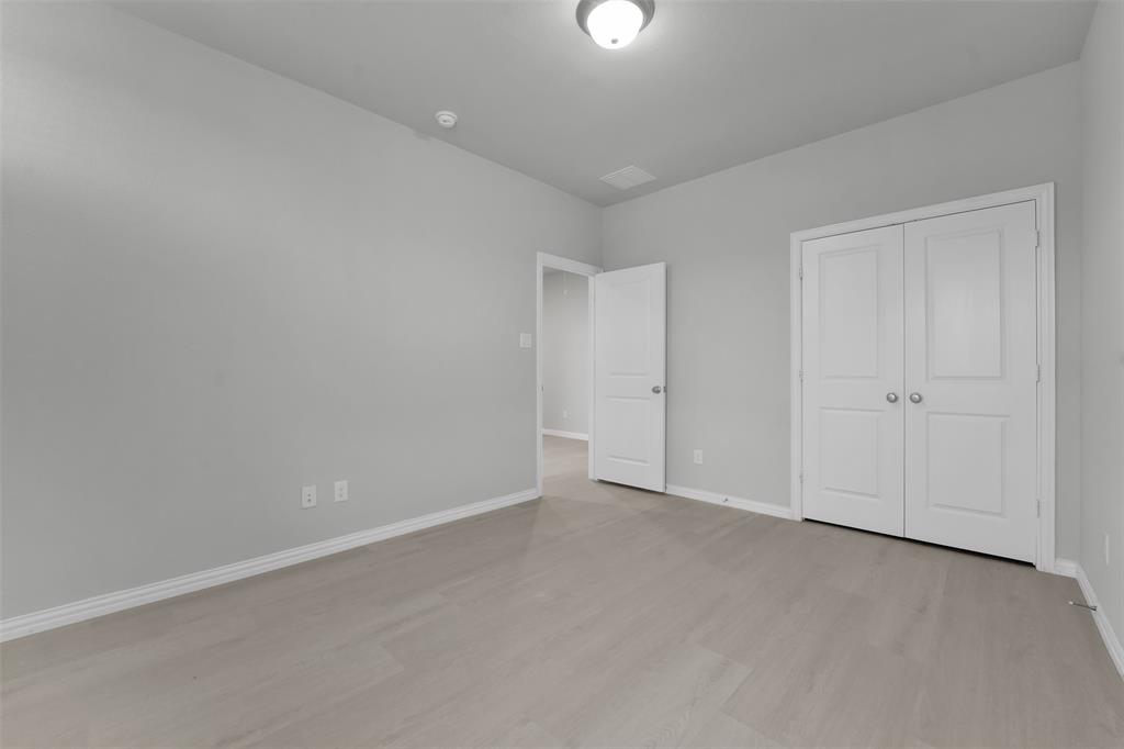 Light wood-finish flooring, white walls, white trim, and white bi-fold doors