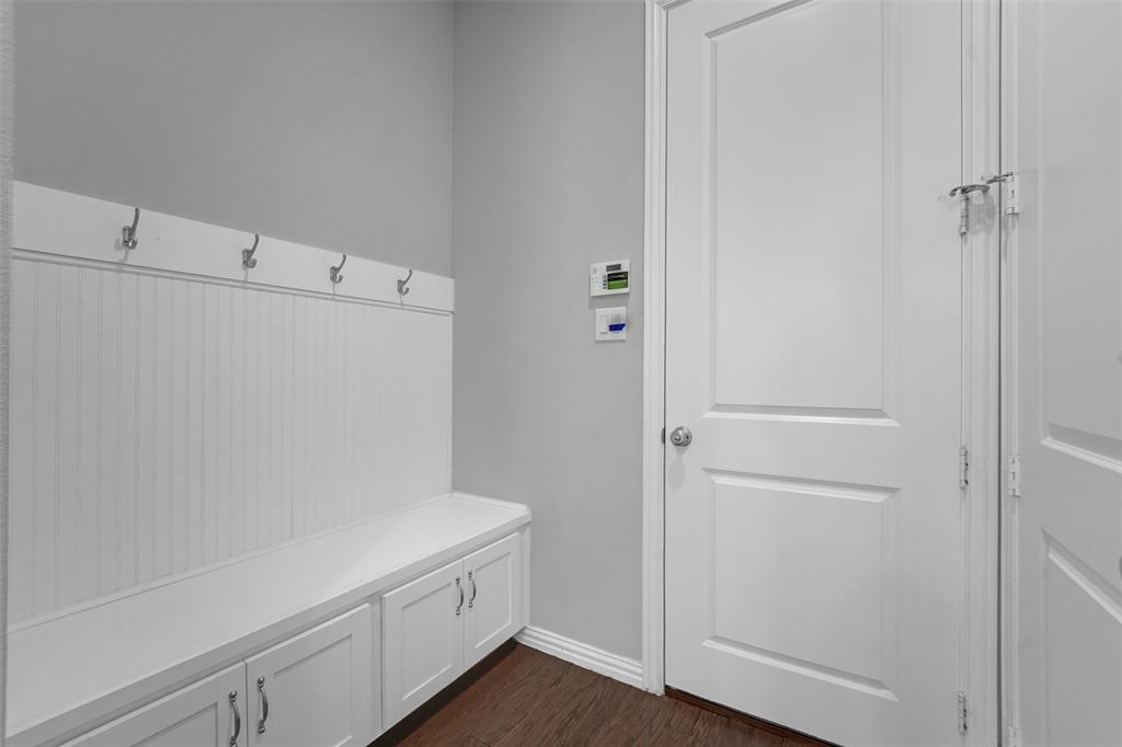 Built-in storage bench with cabinet doors, beadboard paneling, and wall-mounted hooks