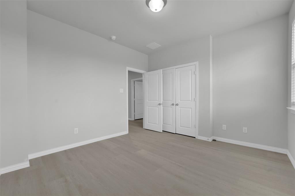 Wood-finish flooring, white bifold closet doors, and a ceiling-mounted light fixture