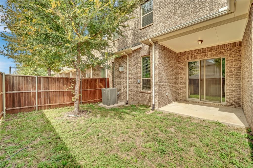 Brick exterior with a covered patio, concrete slab, and sliding glass door