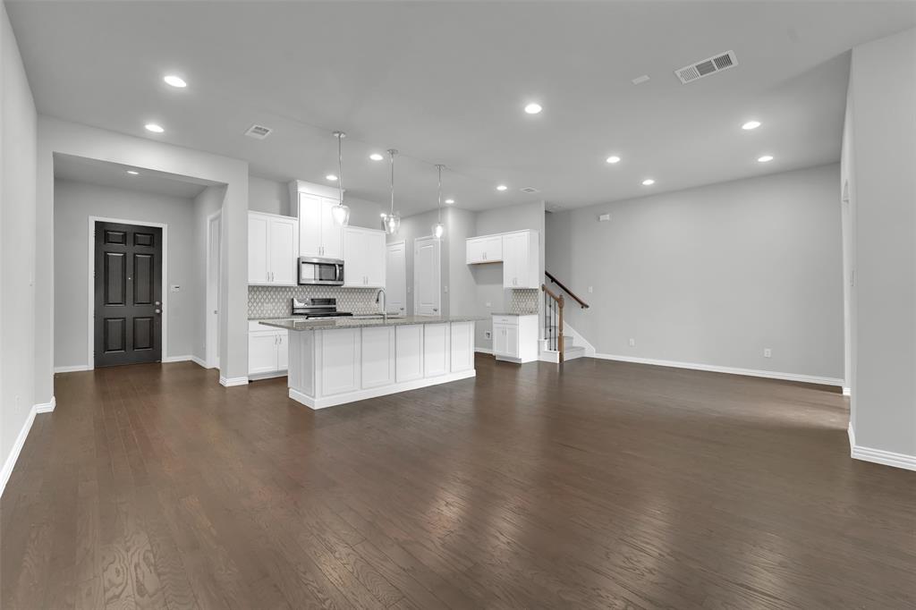 Open-concept living space featuring wood-finish flooring, recessed lighting, and a kitchen island with pendant lighting
