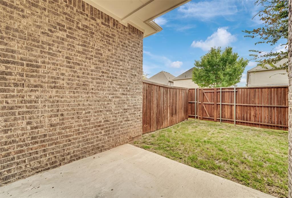 Private fenced backyard featuring a concrete patio and a brick exterior wall