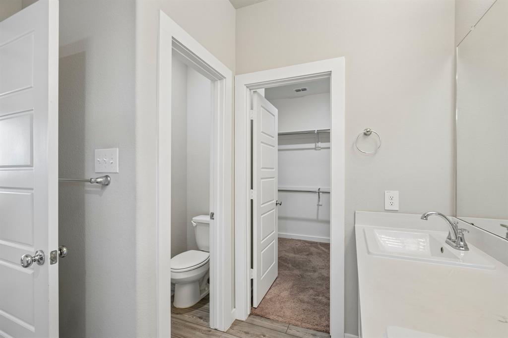 Neutral-toned vanity with an integrated rectangular sink and chrome faucet, large wall-mounted mirror, multiple interior doors with chrome hardware, and dedicated storage area