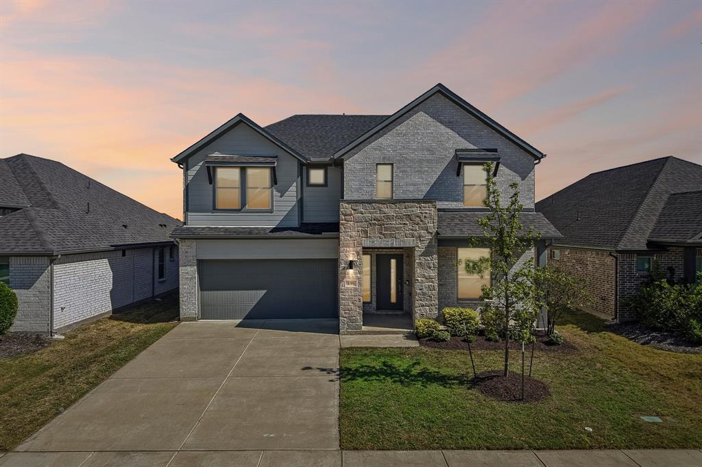 Two-story residence featuring a combination of brick and lap siding, stone veneer accents, multi-gabled rooflines, and an attached two-car garage