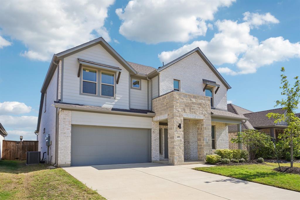 Two-story exterior featuring a combination of light-toned masonry and horizontal siding, a covered entryway, and a dual-car garage