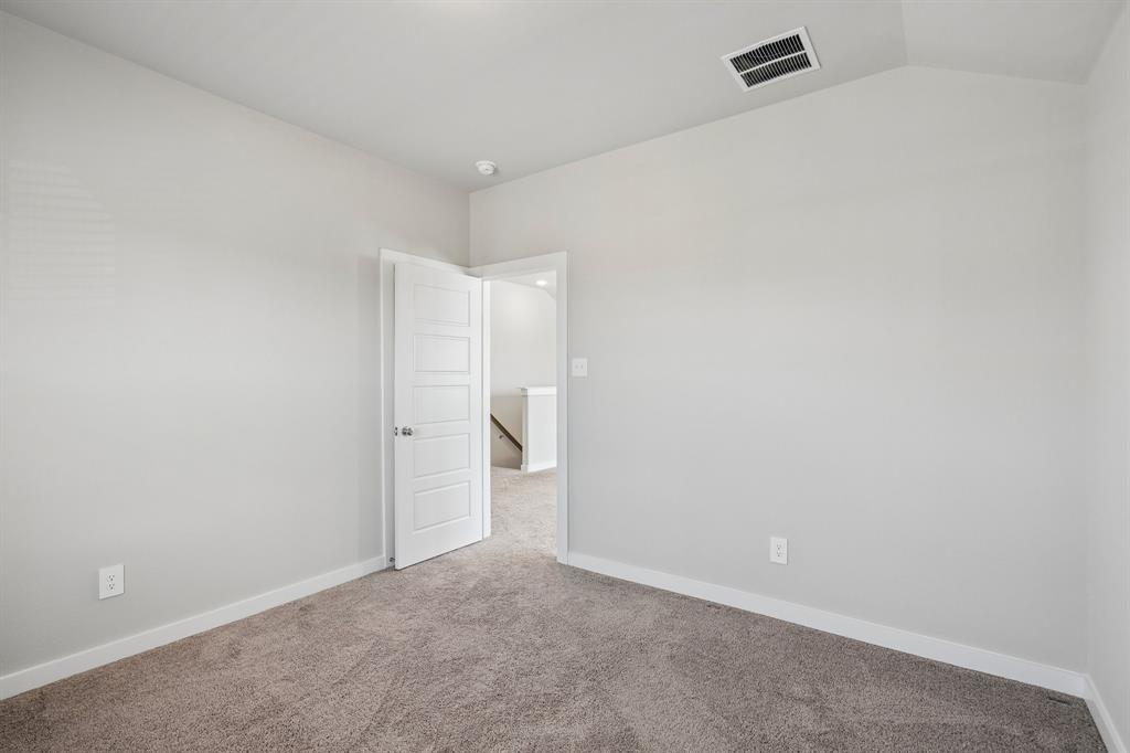Neutral-toned interior space featuring neutral carpeting, a vaulted ceiling, and a solid-core four-panel interior door