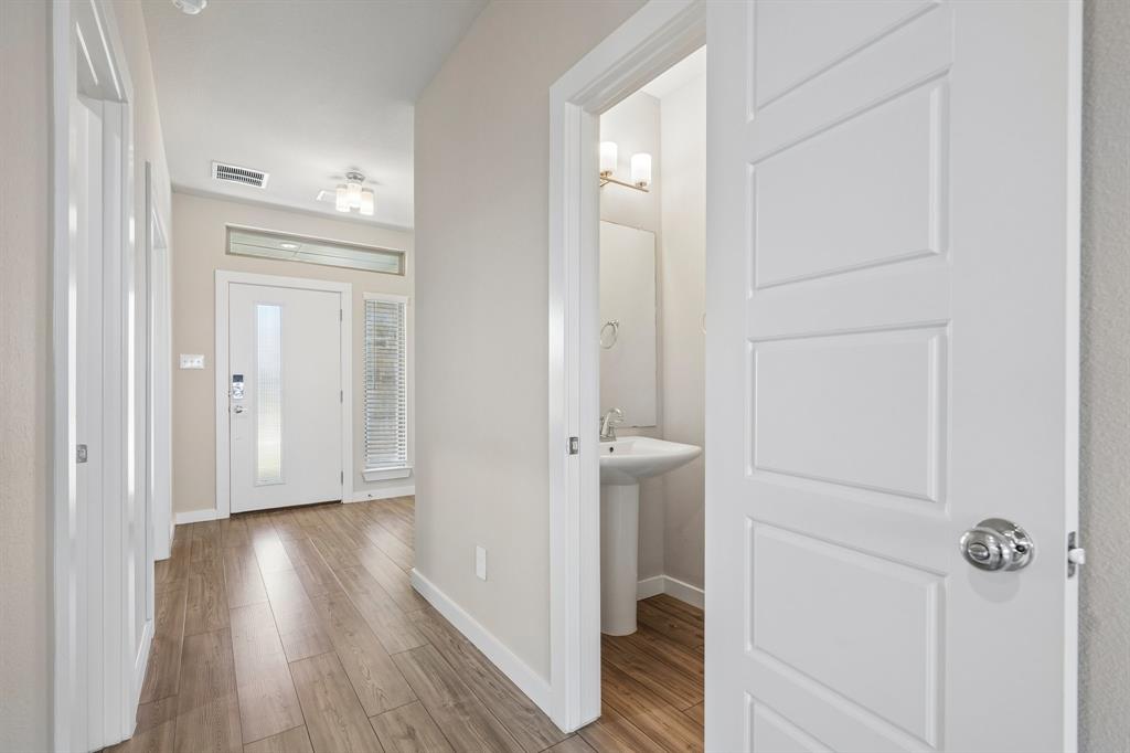 Entryway featuring wood-finish flooring, a white front door with sidelight, a transom window, and a pedestal sink