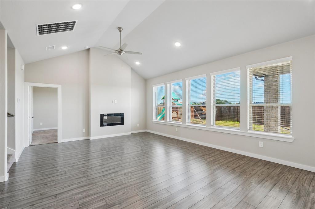 Vaulted ceilings, wood-finish flooring, built-in fireplace, recessed lighting, and expansive windows