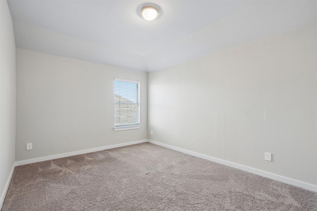 Neutral-toned walls, high-pile carpeting, single window with blinds, and a circular flush-mount ceiling light fixture