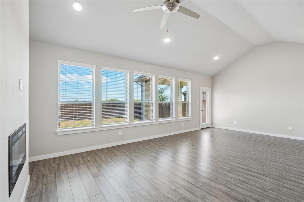 Vaulted ceilings, wood-finish flooring, recessed lighting, wall-mounted electric fireplace, and expansive windows
