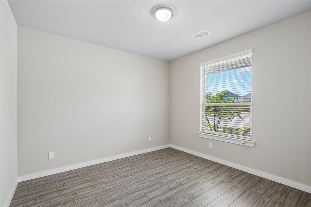 Neutral interior featuring wood-finish flooring, light-toned walls, and a single-pane window with adjustable horizontal blinds