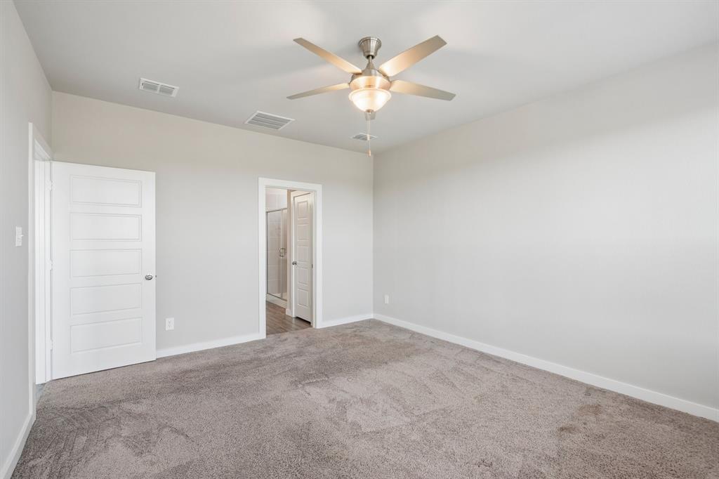 Room featuring neutral-toned carpeting, high ceilings, a multi-blade ceiling fan with an integrated light fixture, and two five-panel interior doors