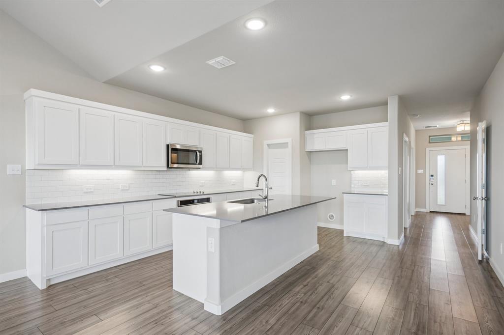 Kitchen featuring white cabinetry, solid-surface countertops, subway tile backsplash, recessed lighting, and wood-finish flooring