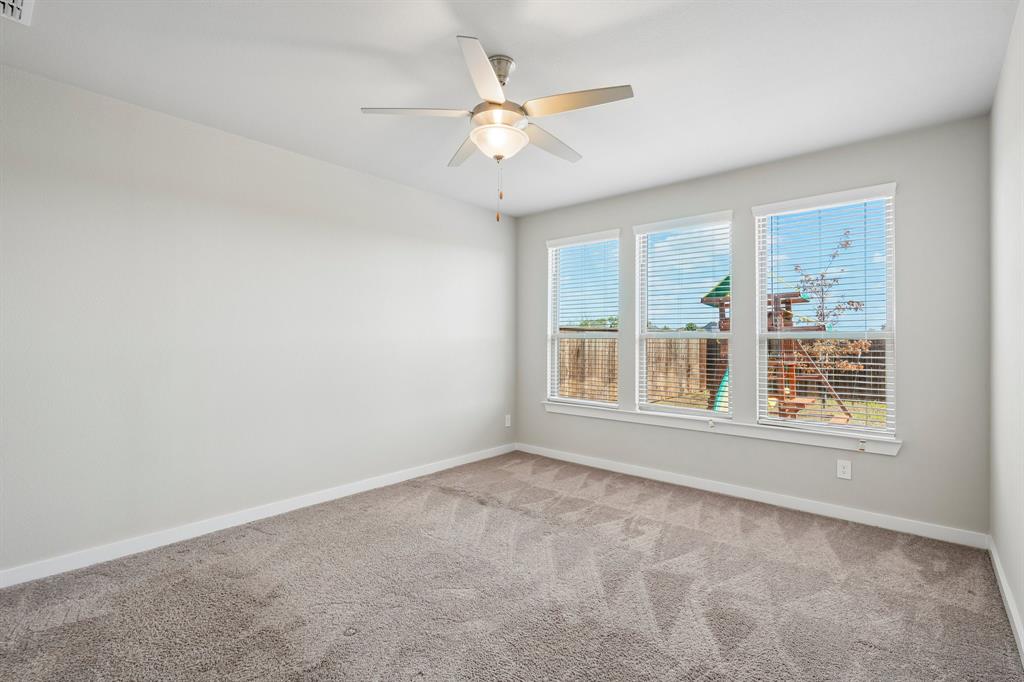 Neutral-toned interior space featuring wall-to-wall carpeting, three windows with horizontal blinds, and a central ceiling fan with an integrated light fixture