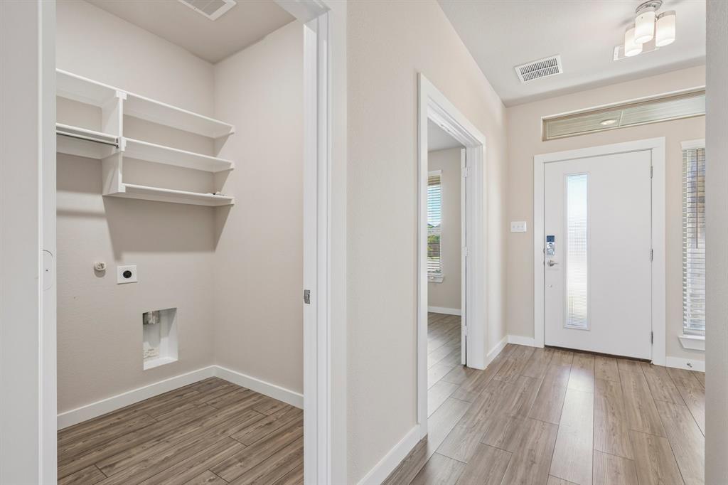Utility area featuring built-in white shelving, wood-finish flooring, and a white exterior door with a glass insert and transom window