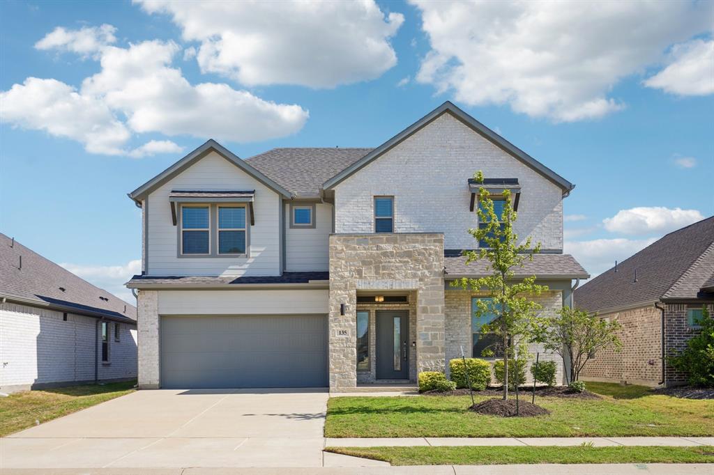 Two-story residence featuring a combination stone and brick facade, gabled roofline, covered entryway, and two-car attached garage