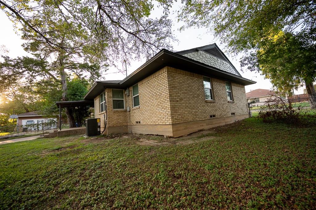 Exterior featuring a tan brick facade, gabled roofline with shingle accents, and a concrete foundation