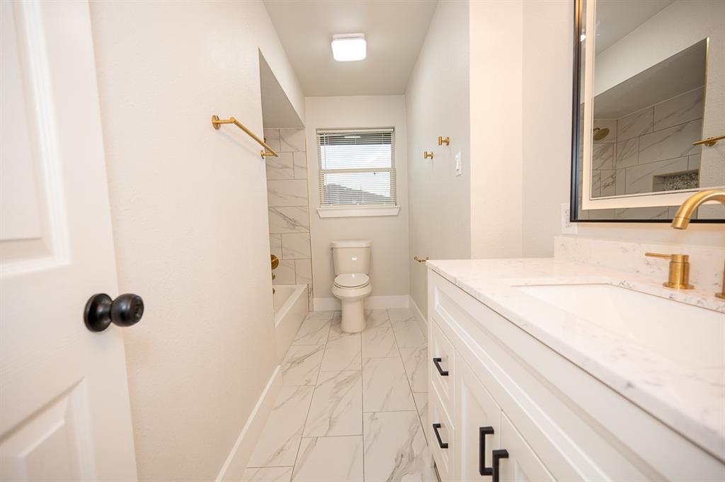 Bathroom featuring a vanity with a light-toned countertop, rectangular undermount sink, and brass-tone hardware