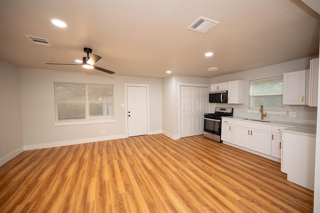 Wood-finish flooring, white shaker-style cabinetry, stainless steel kitchen appliances, recessed lighting, and a ceiling fan