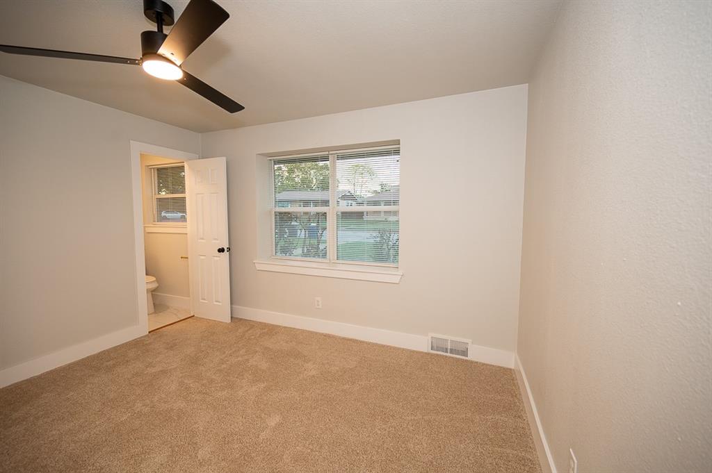 Room featuring neutral carpeting, matte black ceiling fan with integrated lighting, and a multi-pane window