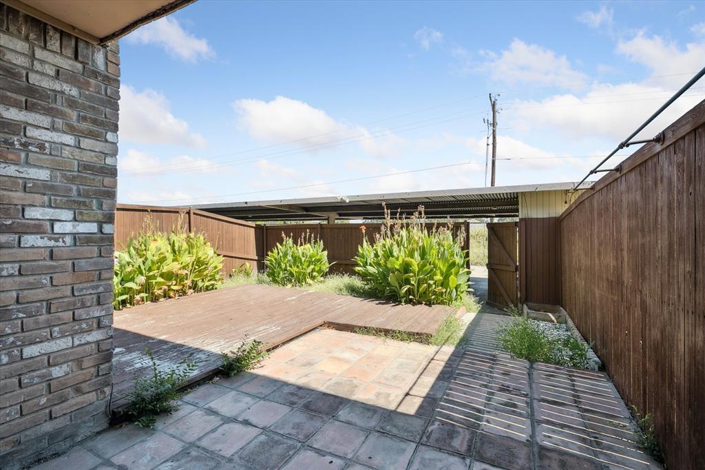 Outdoor area featuring a wood deck, stone-paver patio, brick exterior wall, and wood privacy fencing