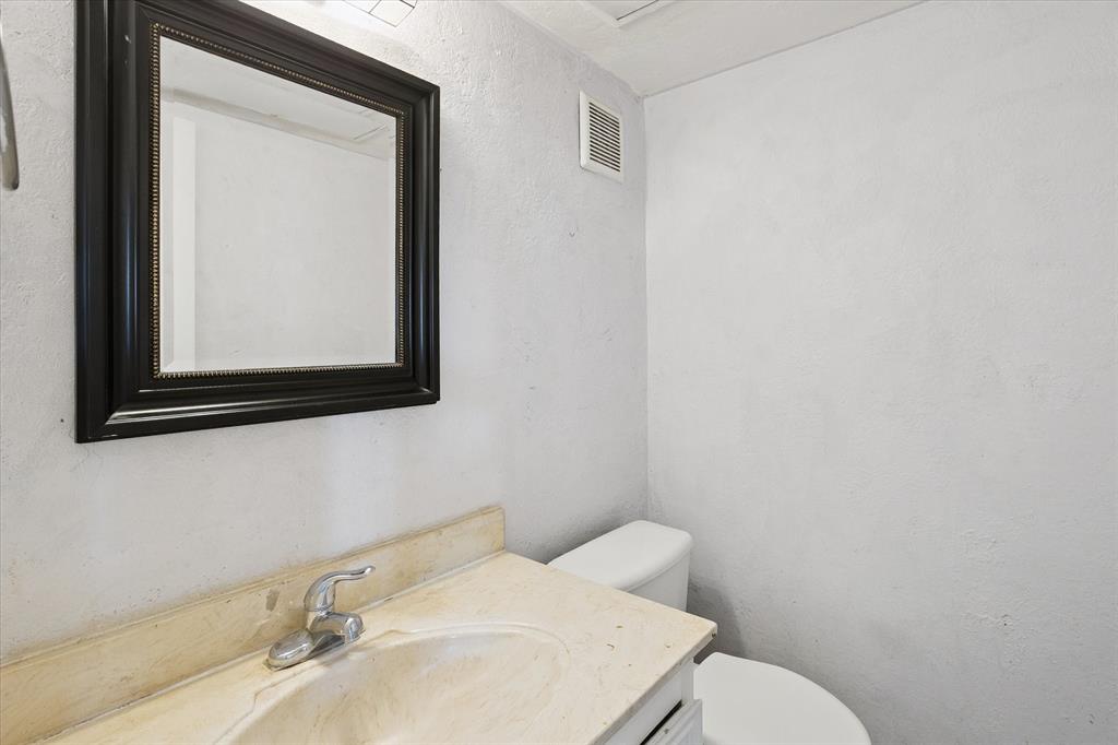 Wall-mounted mirror with a black frame, vanity cabinet with an integrated sink, and polished metal faucet