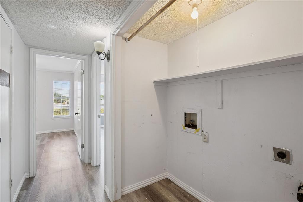 Laundry area featuring wood-finish flooring, a built-in shelving unit, and a metal clothing rod